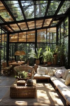 a living room filled with lots of furniture and plants inside of a glass walled building