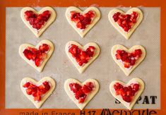 heart shaped cookies with strawberries arranged on a baking sheet for valentine's day