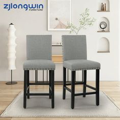 two gray upholstered barstools in front of a white wall