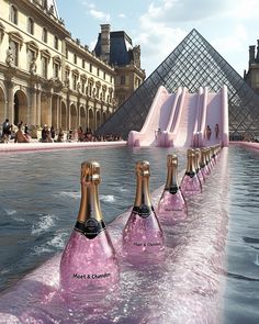 three bottles of champagne sitting in the water next to a pink slide that looks like it's floating