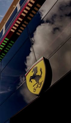 the ferrari logo is reflected in the side of a car's glass window as clouds hover overhead