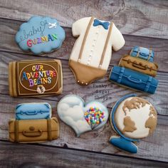 some cookies are on a wooden table with the words, our adventure begins and suitcases