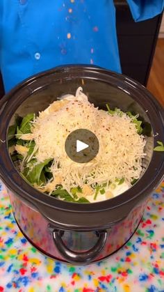 a slow cooker filled with shredded cheese and lettuce sits on a colorful tablecloth