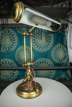 a desk lamp sitting on top of a white table next to a blue cushion and pillow