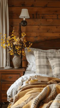 a bed with plaid sheets and pillows in a bedroom next to a lamp on a dresser