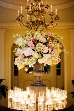 a large vase filled with lots of flowers on top of a table covered in candles