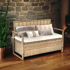 a wicker day bed with pillows on it next to a potted plant