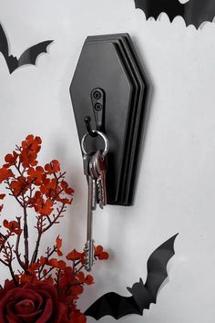 a bunch of keys hanging from a hook on a wall next to flowers and bats