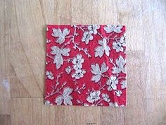 a piece of red fabric with white flowers on it sitting on top of a wooden floor