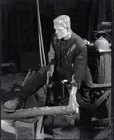 an old black and white photo of a man working on a piece of wood with a hammer