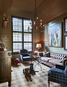 a living room with couches, chairs and deer heads on the wall behind them