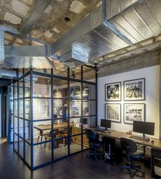 an office with glass partitions and wood flooring in the center, along with pictures on the wall