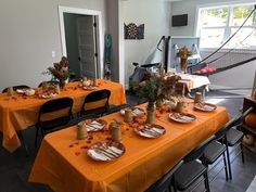 two tables are set with orange tablecloths and place settings for the dinner party