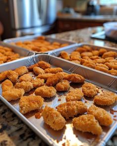 two trays filled with fried food sitting on top of a counter next to each other