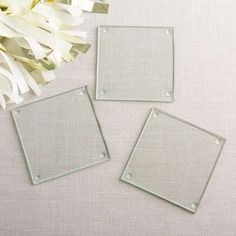 three square glass plates sitting on top of a table next to white flowers and greenery