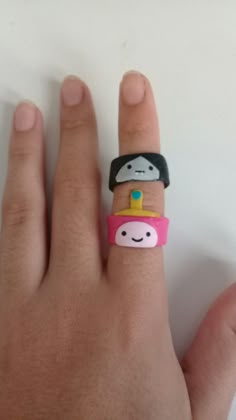 a person's hand with a ring that has a cartoon character on the middle