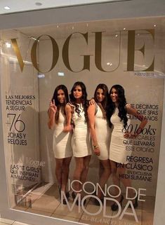 three beautiful young women standing in front of a magazine window