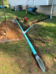 a blue pipe laying in the ground next to a house