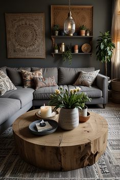 a living room with grey couches and wooden table in the centerpiece, surrounded by potted plants