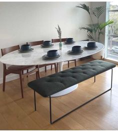 a white table with black plates on it and a bench in front of the table