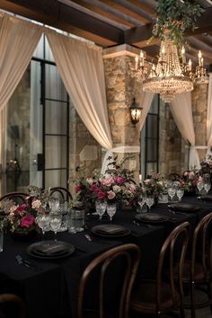 a long table is set up with black linens and pink flowers in vases