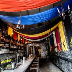 the interior of a bar with colorful drapes hanging from the ceiling and bottles on the shelves