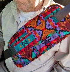 a man sitting in the back seat of a car with a colorful bag on it