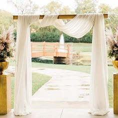 an outdoor ceremony with white drapes and flowers