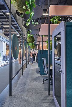 an office building with plants hanging from the ceiling and people walking down the sidewalk in the background