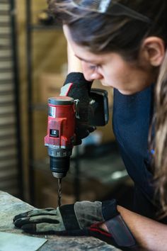 a woman using a driller on a piece of wood