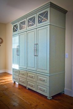 a large blue armoire sitting on top of a wooden floor next to a clock