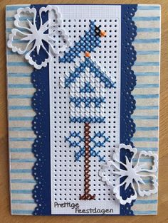 a cross stitch christmas card with snowflakes and a blue bird on the tree