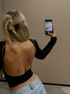 a woman taking a selfie in front of a mirror with her back turned to the camera