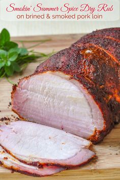 sliced ham sitting on top of a wooden cutting board next to fresh herbs and leaves