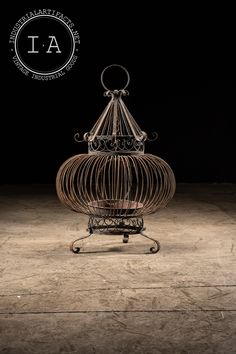 a birdcage sitting on top of a wooden floor next to a black background