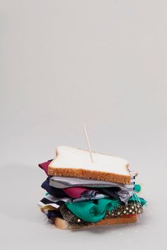 a sandwich sitting on top of a pile of clothes with a toothpick in it