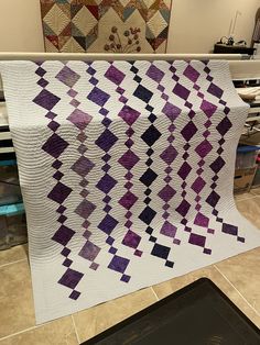 a purple and white quilt sitting on top of a table