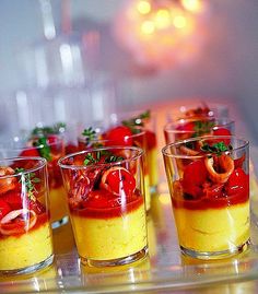 small glasses filled with food sitting on top of a table