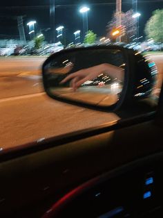 a car's rear view mirror with a hand on it