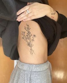 a woman's lower back with flowers on her left side and tattoos on her right arm