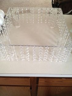 a clear glass tray sitting on top of a table next to a white vase and two candles