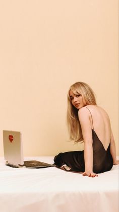 a woman is sitting on the bed with her laptop