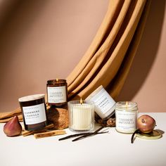 an assortment of candles, apples and cinnamon sticks sit on a table next to a curtain