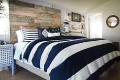 a bed with blue and white striped comforter next to a wall made from wood planks