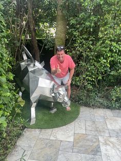 a man standing next to a metal sculpture of a horse in the middle of a garden