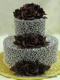 a three tiered cake with chocolate roses on top