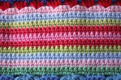 a close up view of a crocheted blanket with multicolored yarns