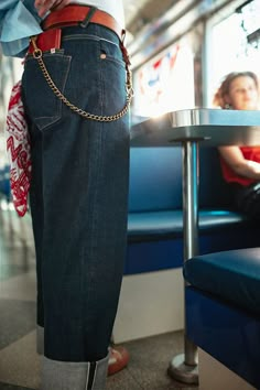 a person standing on a train with their pants tied to their hips and wearing jeans