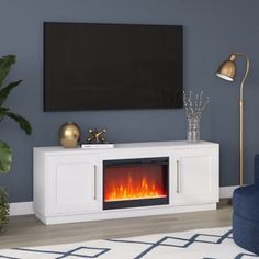 a living room with a large television and fire place in the center, next to a blue chair