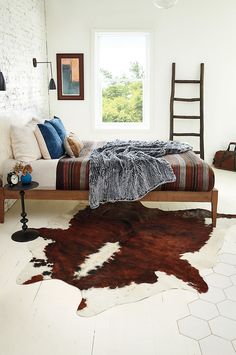 a bedroom with a cow hide rug on the floor and a bed in front of a window